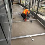 Worker securing aluminum track system on Burnaby balcony