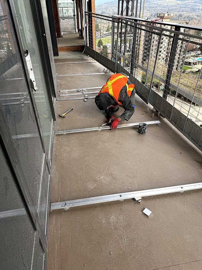 Worker securing aluminum track system on Burnaby balcony