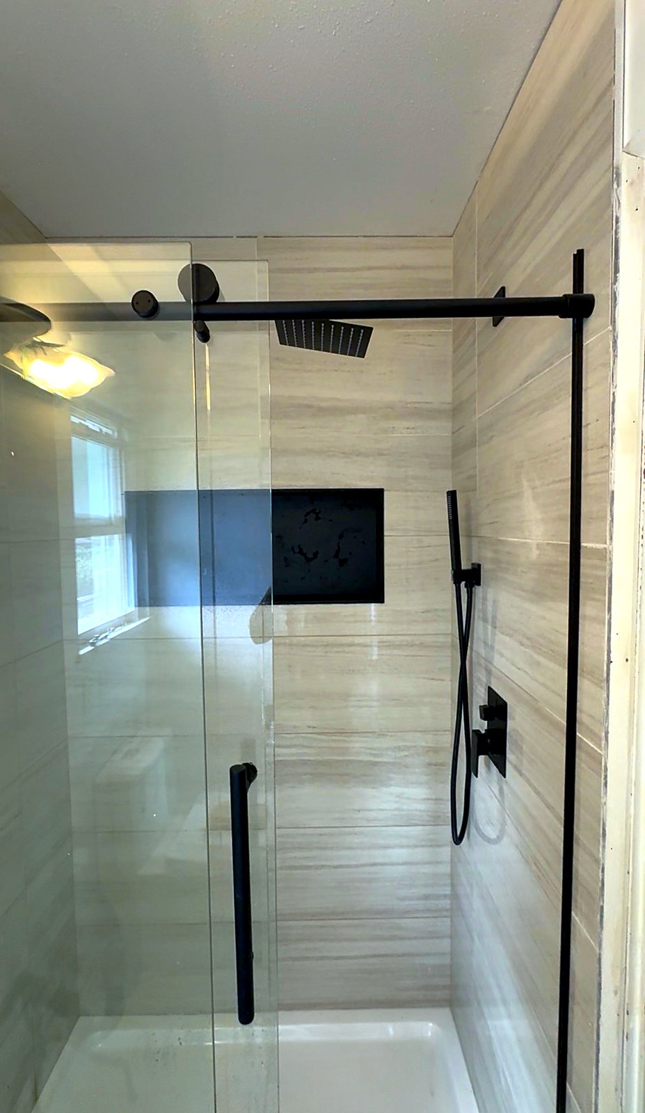Finished shower rebuild in Surrey, BC with matte black fixtures and sliding glass door