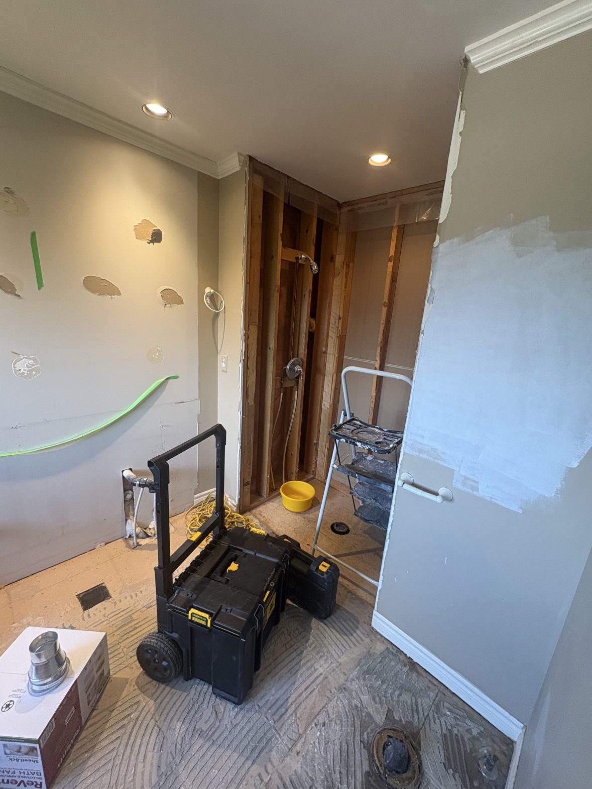 A condo bathroom at demolition stage — fixtures out, plumbing exposed, floors protected